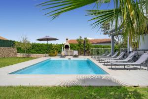 una piscina con sedie e un ombrellone di Luxury Villa - Amazing Sea Views a Son Bou