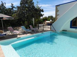 a swimming pool with two chairs and a building at Quinta do Pomarinho with private pool in Tavira