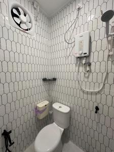 a white tiled bathroom with a toilet and a sink at Homestay Ayuni in Kuala Terengganu +2 photos
