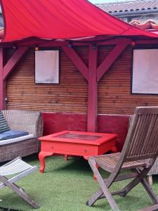 une table et des chaises rouges devant un bâtiment dans l'établissement Chez Solange et Paul, à Mézos