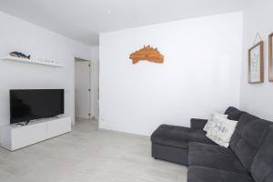 Una sala de estar con un sofá negro y un televisor de pantalla plana. en Villa Izarenar, en Cala Blanca