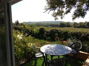 a table and chairs on a patio with a view of a field at Au petit bonheur chez l'habitant in Ferques