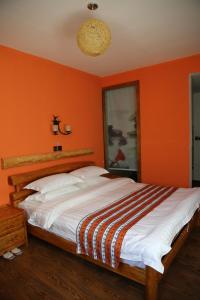 a bedroom with orange walls and a large bed at Nirvana Hotel, Restaurant & Bar in Xiahe