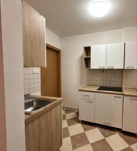 a kitchen with white cabinets and a sink and a tiled floor at Apartma Studio Enej Piran in Piran +9 photos