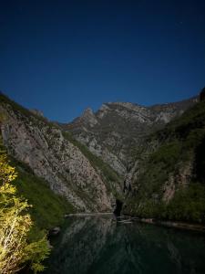 a body of water in front of a mountain at Riverside Komani Lake in Koman
