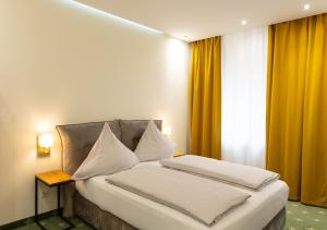 a bedroom with a bed with white sheets and yellow curtains at City Apartments - Nürnberg Altstadt in Nürnberg +42 photos