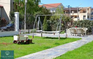 a playground with a swing and chairs in a yard at Mida Summer Villa in Mamaia Sat/Năvodari