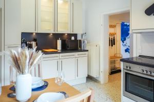a kitchen with white cabinets and a wooden table at 7Seas City-Apartment Kaiserslautern - Balkon l NETFLIX l 24h Self Check-in in Kaiserslautern