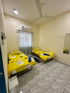 two beds in a room with yellow sheets at Teratak Manis Homestay in Kuantan