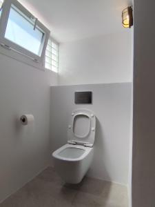 a white toilet in a bathroom with a window at Milos Pollonia Apartment in Mesochórion +22 photos