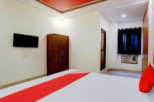 a bedroom with a bed and a tv on the wall at Hotel O Elibrista in Meerut