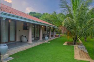 a house with a palm tree next to a yard at Villa Green Cocos in Katuwana