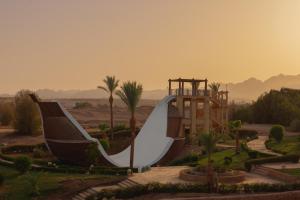 a slide in a park with a building and palm trees at JAZ Sharm Dreams in Sharm El Sheikh