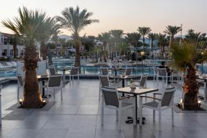 a hotel patio with tables and palm trees and a pool at JAZ Sharm Dreams in Sharm El Sheikh