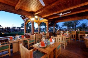 a restaurant with wooden tables and chairs and palm trees at JAZ Sharm Dreams in Sharm El Sheikh