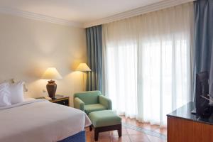 a hotel room with a bed and a chair and a television at JAZ Sharm Dreams in Sharm El Sheikh