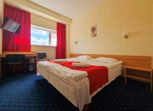 a hotel room with a large bed with red curtains at ----------------------------- Via Baltica Panevezys in Panevėžys
