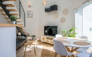 un soggiorno con tavolo, sedie e TV di Escapade Tropicale fibre, terrasse,parking,clim a Millau