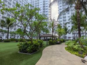 马尼拉La Vie Riche Holiday Homes - Cozy 1BR Apartment near MOA的棕榈树公园和建筑中的步行道