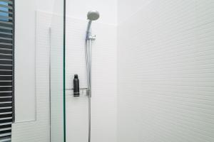 a shower with a glass door next to a building at Muizenberg Coastal Hideaway by Surfers Corner in Muizenberg +13 photos