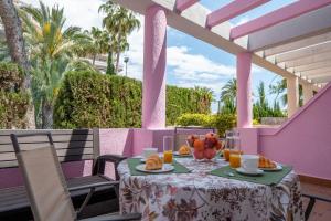 Una mesa con un bol de fruta y zumo en un patio. en Bungalow a pie de playa, en Ifach