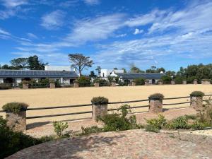 a fence in front of a field with a building at Dunkes Organic Equestrian Estate in George