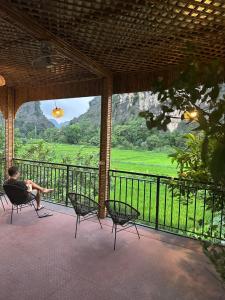 a person sitting in a chair on a porch with a view at Tam Coc Min House in Vũ Lâm