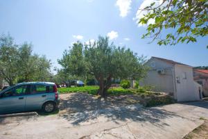 samochód zaparkowany na podjeździe obok drzewa w obiekcie Apartment Neno w mieście Sutomišćica