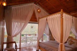 a bedroom with a canopy bed and a balcony at Whispering Oaks by Happy Himalayan in Rāmgarh