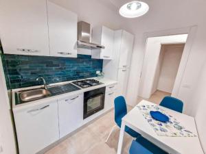 een keuken met witte kasten en een tafel met blauwe stoelen bij Holy Dove by Wonderful Italy in Cefalù