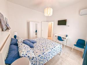 een slaapkamer met een bed met blauwe kussens en een bureau bij Holy Dove by Wonderful Italy in Cefalù