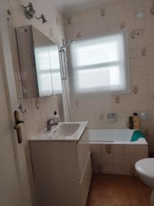 Un baño con lavabo, bañera y espejo. en En el Parque de las Meanas., en Avilés