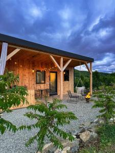 a wooden cabin with a black roof and a patio at KUBIQ TRANSALPINA in Petreşti
