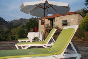 two lawn chairs and an umbrella and a table at Casa do Vale - Douro Valley Cottage in Resende