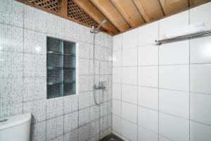a white tiled bathroom with a toilet and a window at Hotel O Putroyono Homestay in Mendut +51 photos