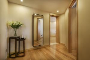 a hallway with a mirror and a vase of flowers on a table at Green Court Residence Jinqiao Diamond Shanghai in Shanghai