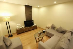 a living room with a couch and a tv at Green Court Residence Jinqiao Diamond Shanghai in Shanghai