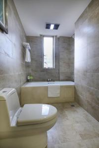 a bathroom with a toilet and a bath tub at Green Court Residence Jinqiao Diamond Shanghai in Shanghai