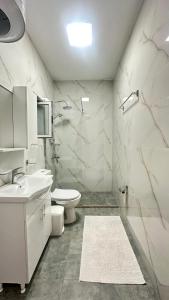 a white bathroom with a toilet and a sink at Villa Center in Tirana