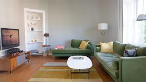 a living room with two green couches and a tv at Authentic Amsterdam Apartment RAI in Amsterdam