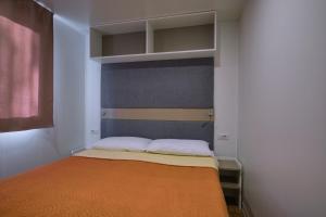 a small bedroom with a bed with an orange blanket at Camping Trasimeno in Passignano sul Trasimeno +46 photos