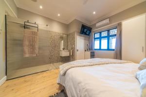 a bedroom with a large bed and a shower at Room 3 - LEO Sky Guest House in Simondium