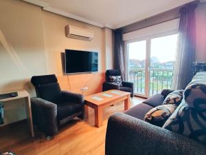 a living room with a couch and chairs and a tv at Modern duplex in downtown Cambados in Cambados