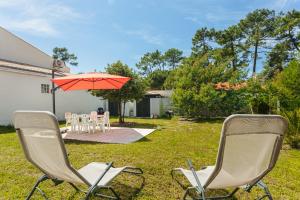 two chairs and an umbrella in a yard at Grande maison entre plage et foret in Saint-Trojan-les-Bains
