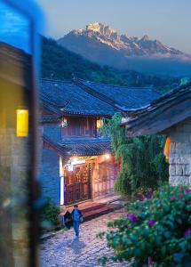 a woman walking in front of a building at Lijiang half yard hotel in Lijiang