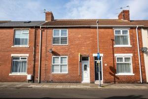 a red brick house with a white door at Meldon Terrace Parking Wi-fi in Woodhorn