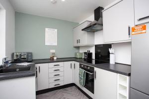 a kitchen with white cabinets and black counter tops at Meldon Terrace Parking Wi-fi in Woodhorn