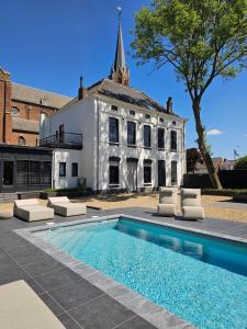 a house with a swimming pool in front of a building at Roomz B&B in Kloosterzande