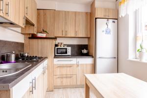 a kitchen with wooden cabinets and a white refrigerator at BOSMAN Karwia - Pokoje 100m od Plaży in Karwia