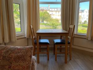 a table and chairs in a room with a window at The Hutchinson Apartments in Douglas